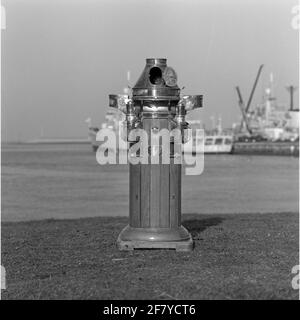 Boiler house for the magnetic compass of the Marine Barracks Willemsoord, placed on the lawn on the port basin side. In the background a standard frequency of the Kortenaerklass. Stock Photo