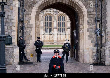 The day after the death at age 99 of Prince Phillip, the Duke of Edinburgh, consort to Queen Elizabeth II, armed police officers and a woman member of the Royal Household stand outside Windsor Castle where the Queen has been isolating throughout the Coronavirus pandemic, on 10th April 2021, in London, England. Stock Photo