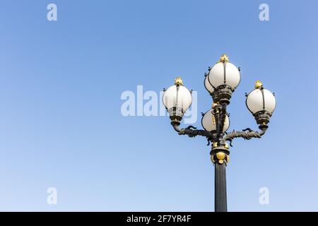 Vingate style street lamp with golden ornaments and round bulbs against clear blue sky, Dubai, United Arab Emirates. Stock Photo