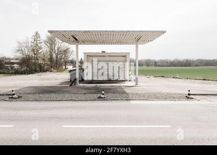 White roofing and building of a small deserted closed petrol station on a rural country road in spring in Bavaria, Germany Stock Photo