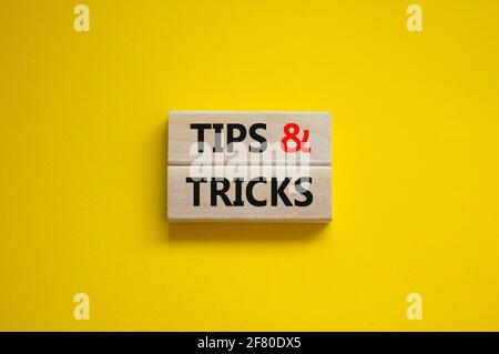 Tips and tricks symbol. Wooden blocks with words 'Tips and tricks'. Beautiful yellow background. Business, tips and tricks concept. Copy space. Stock Photo