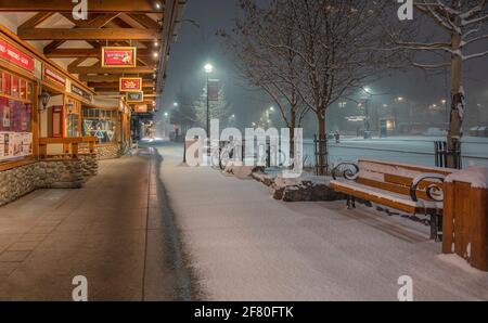 Banff, Alberta, Canada – April 10, 2021:  Exterior view of Banff Avenue business during an early morning snowfall Stock Photo