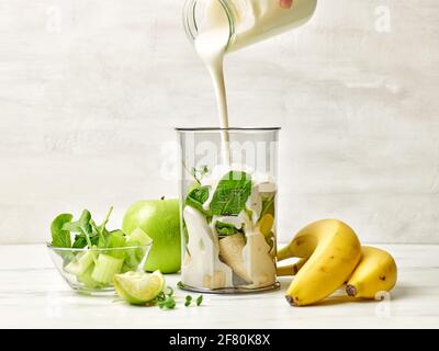 cook adding yogurt into blender container on kitchen table, selective focus Stock Photo