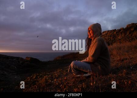 very cheerful young woman happy smiling looking at a sunset coast of chile on vacation Stock Photo