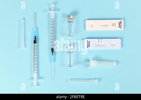 Rapid antigen test and vaccine vials with syringes. Tools to fight Corona Virus pandemic. Stock Photo