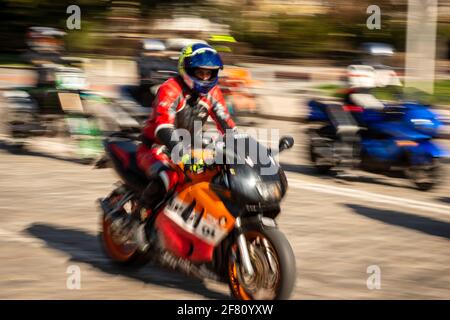Panning shot view of group of unidentified bikers riding sport motorbikes in urban environment in sunny weather Stock Photo