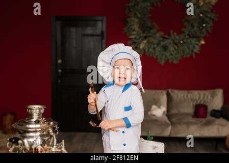 Portrait of a little boy cook holding pan at the kitchen. Different occupations. Isolated over white background. Twin brothers Stock Photo