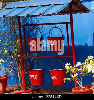 fire and safety metal red bucket stored in racks Stock Photo