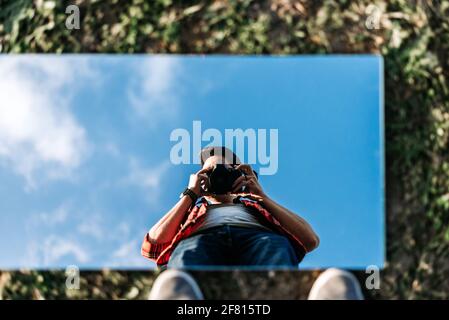 Young photographer taking a selfie on a mirror on the ground Stock Photo