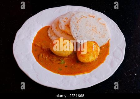 traditional kerala style breakfast rice cake known as appam with egg curry Stock Photo