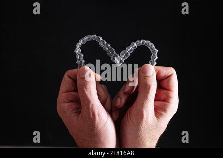 Doctor hands holding heart shaped transparent dental aligners Stock Photo