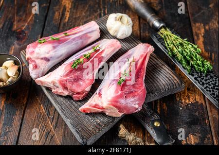 Raw veal shanks meat on a cutting board with herbs. Dark wooden background. Top view Stock Photo
