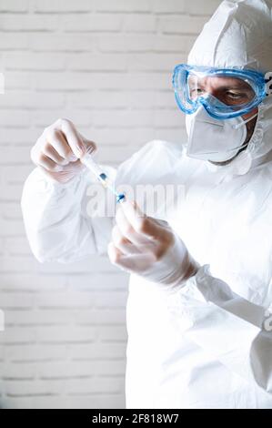 Male nurse in protective workwear filling injection Stock Photo