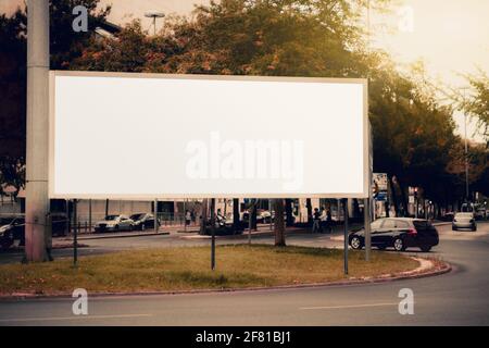 A huge rectangular white empty advertising billboard template on the beltway; a mock-up of a blank advert poster placeholder in the roundabout; a mock Stock Photo