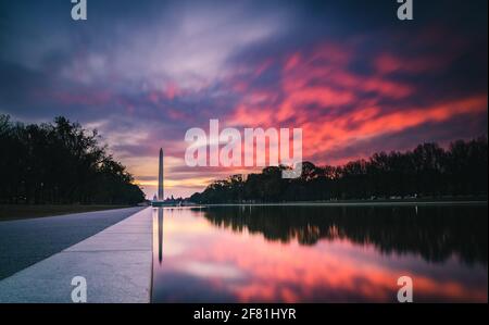 A red and indigo sunrise over the Reflecting Pool along the National Mall in Washington DC. Stock Photo