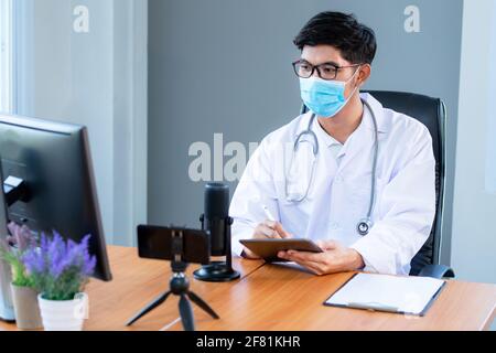 New normal, medical team wearing medical masks technology network team meeting concept. Doctor at a table discussing a patients records working, Onlin Stock Photo