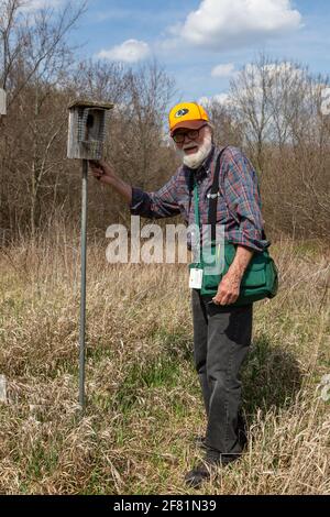 Volunteer birdkeeper Robert Bredemeyer poses next to a birdhouse in the brush at Metea County Park in Allen County, Indiana, USA. Stock Photo