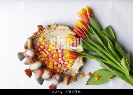 a bouquet of five tulips on a background and a plate with square sweets Stock Photo