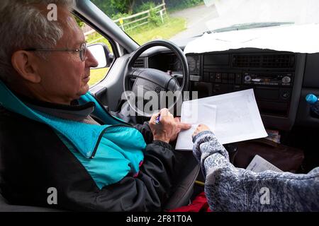 Father and daughter discussing route in car. From above senior man and adult woman trying to figure out directions while sitting in car during trip. Stock Photo