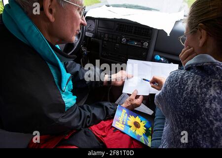 Father and daughter discussing route in car. From above senior man and adult woman trying to figure out directions while sitting in car during trip. Stock Photo