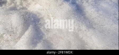 Close-up of dirty snow with frozen ice in early spring. Sunlight and shadows on snow texture, the concept of climate and seasonal weather. Stock Photo