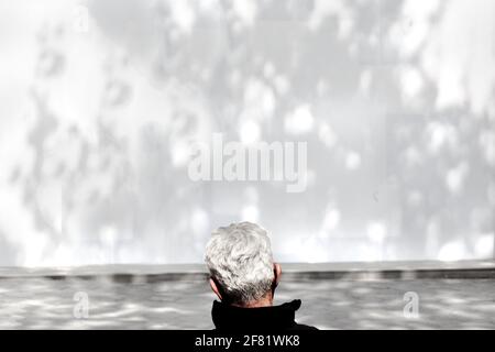 Man staring at dappled light on painted white board. Stock Photo