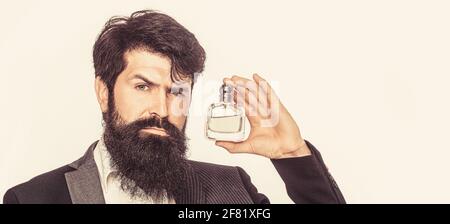 Perfume or cologne bottle and perfumery, cosmetics, scent cologne bottle, male holding cologne. Masculine perfume, bearded man in a suit. Male holding Stock Photo