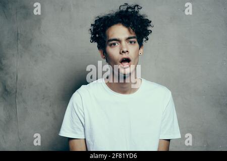 guy with curly hair in a white t-shirt sits on chairs studio Stock Photo