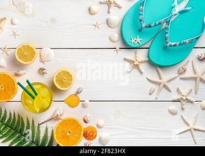 Sea background with seashells, iced juice, fruit and flip flops on a white background. Top view with copy space. Stock Photo