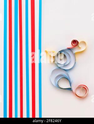 A cute parrot is obtained with the artistic technique known as paper quilling on a white background and strips of paper Stock Photo