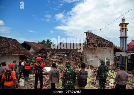 East Java, Indonesia. 11th April, 2021. (Members of search and rescue team are seen near damaged houses after a 6.1 magnitude quake hit Majang Tengah village in Malang, East Java, Indonesia, April 11, 2021. Six people were killed, another one was seriously injured, and scores of buildings were damaged after a 6.1-magnitude quake rocked Indonesia's western province of East Java on Saturday, officials said. The earthquake struck at 2 p.m. Credit: Xinhua/Alamy Live News Stock Photo