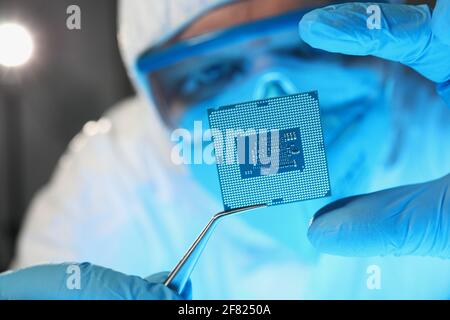 Scientist developer in protective suit holds microcircuit Stock Photo