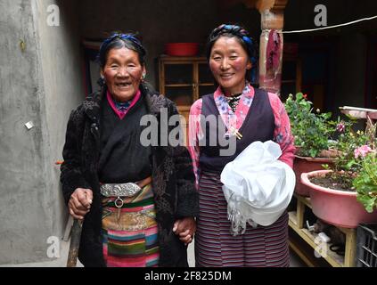 (210411) -- XIGAZE, April 11, 2021 (Xinhua) -- Lhapa (L) and her daughter pose for a photo in Puga Village of Xigaze, southwest China's Tibet Autonomous Region, March 20, 2021. Lhapa, born in 1945, is a villager in Puga Village. When she was a child, her mother became blind due to overwork and lost the ability to work. The serf owner drove her out of the manor, and Lhapa's mother had to beg everywhere with her sister for a living. In 1959, during the democratic reform in Tibet, the Lhapa's family were finally reunited and alloted 24 mu (about 1.6 hectare) of land, six sheep and two cows. Th Stock Photo