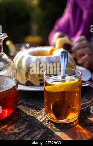 Tea in glass cup with bundt cake on table. Serving dessert and hot drink outdoors Stock Photo