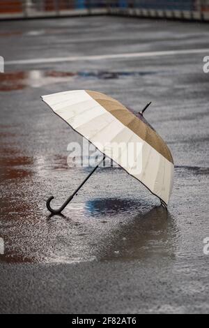 Umbrella in rain on empty street. Bad weather and overcast in city Stock Photo