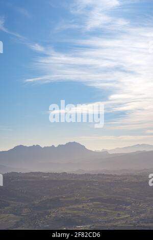 Mountain between villages on a clear day with few clouds, the sea in the background. In Alicante, Spain. Stock Photo