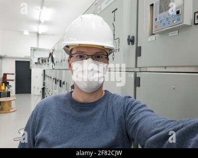 Young engineer working in electrical substation wearing a face mask. Stock Photo