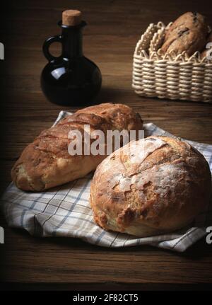 Loaves of bread and a balsamic vinegar bottle in a rustic setting. Stock Photo