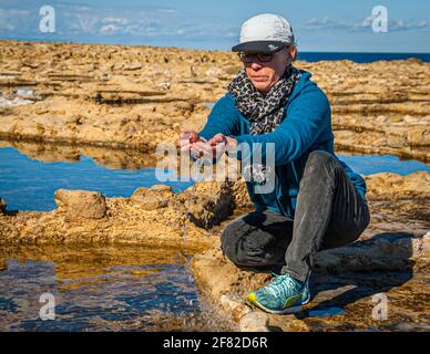 Food journalist Angela Berg scoops the salty water from an ancient salt pan Stock Photo