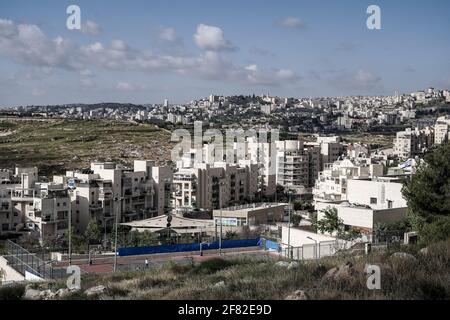 Jerusalem, Israel. 11th April, 2021. Construction is ongoing in Homat Shmuel, or Har Homa, in East Jerusalem, with the Palestinian city of Bethlehem depicted in the far background, on land expropriated in 1991, as a Jerusalem committee approves a plan for an additional 540 housing units. The Jewish neighborhood beyond the Green Line, the armistice demarcation line before the 1967 Six Day War that separates Israel and the West Bank, is considered an illegal Israeli settlement by much of the world. The plan is the first major building project across the pre 1967 boundaries since U.S. President B Stock Photo