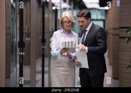 Diverse employees work on tablet discussing ideas Stock Photo