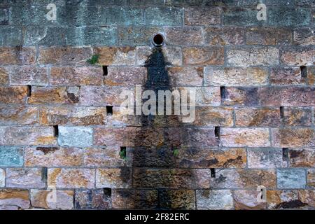 water flowing out of a drain leaves a stain down the side of the wall Stock Photo