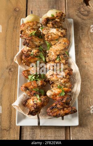 British chicken wings that have been marinaded in Ras el Hanout Moroccan spices before being skewered and grilled at home. England UK GB Stock Photo