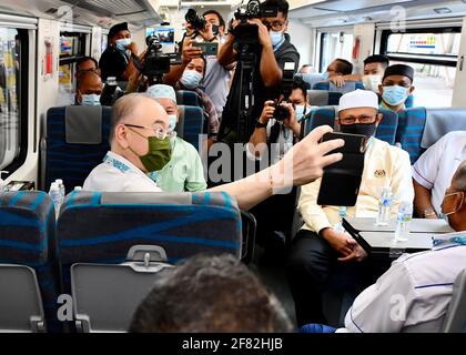 Kota Bharu, Malaysia's northern Kelantan state. 11th Apr, 2021. Malaysian Transport Minister Wee Ka Siong (L, front) takes a ride on the Diesel Multiple Unit train in Kota Bharu, the capital of Malaysia's northern Kelantan state, April 11, 2021. The Diesel Multiple Unit (DMU) trains manufactured by China Railway Rolling Stock Corporation (CRRC) Zhuzhou Electric Locomotive Co., Ltd were launched into operations on Sunday, which will boost connectivity and facilitate travel in Malaysia's eastern coast area. Credit: Zhu Wei/Xinhua/Alamy Live News Stock Photo