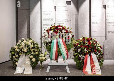 Duesseldorf, Germany. 11th Apr, 2021. Three large wreaths of flowers stand in the memorial hall of Düsseldorf Airport in front of a wall in which the names of the victims of the fire accident on 11 April 1996 are engraved. In front of it are . Today is the 25th anniversary of the fire disaster at Düsseldorf Airport. On 11 April 1996, 17 people died and 88 were injured in the most serious fire disaster ever to occur at a German airport. Credit: Marcel Kusch/dpa/Alamy Live News Stock Photo