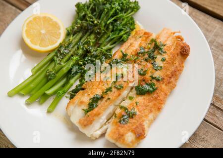 Fillets of fried Starry Smooth Hound, Mustelus asterias, that have first been coated in flour and then served with boiled broccoli and lemon. England Stock Photo