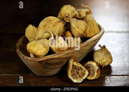 dried wild figs in a bowl made of olive wood isolated on rustic wooden table Stock Photo