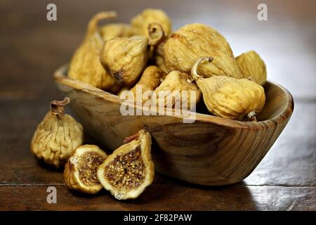 dried wild figs in a bowl made of olive wood isolated on rustic wooden table Stock Photo