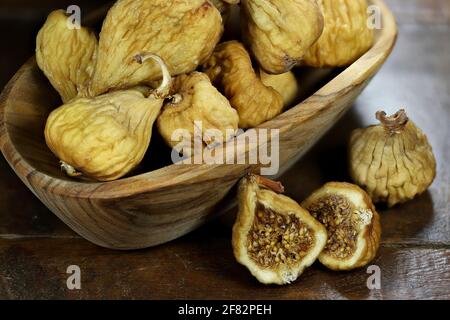 dried wild figs in a bowl made of olive wood isolated on rustic wooden table Stock Photo