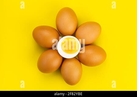 Top view group of whole chicken eggs and a half boiled egg deocorated on yellow background Stock Photo